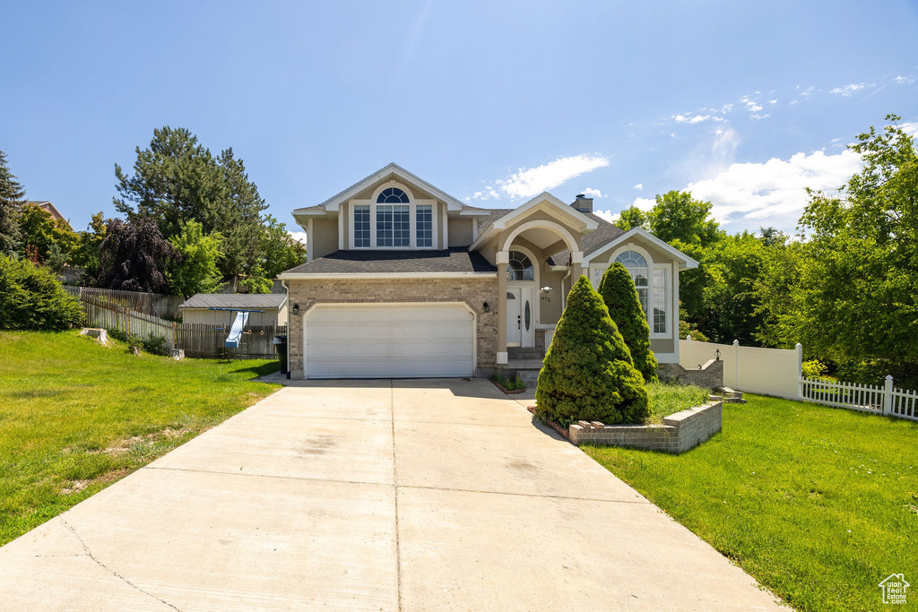 View of front of home featuring an attached garage, concrete driveway, stucco siding, and a chimney