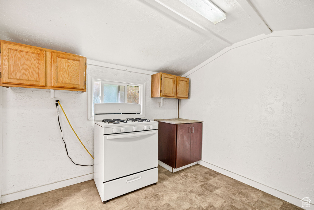 Kitchen with white gas range, lofted ceiling, and light countertops