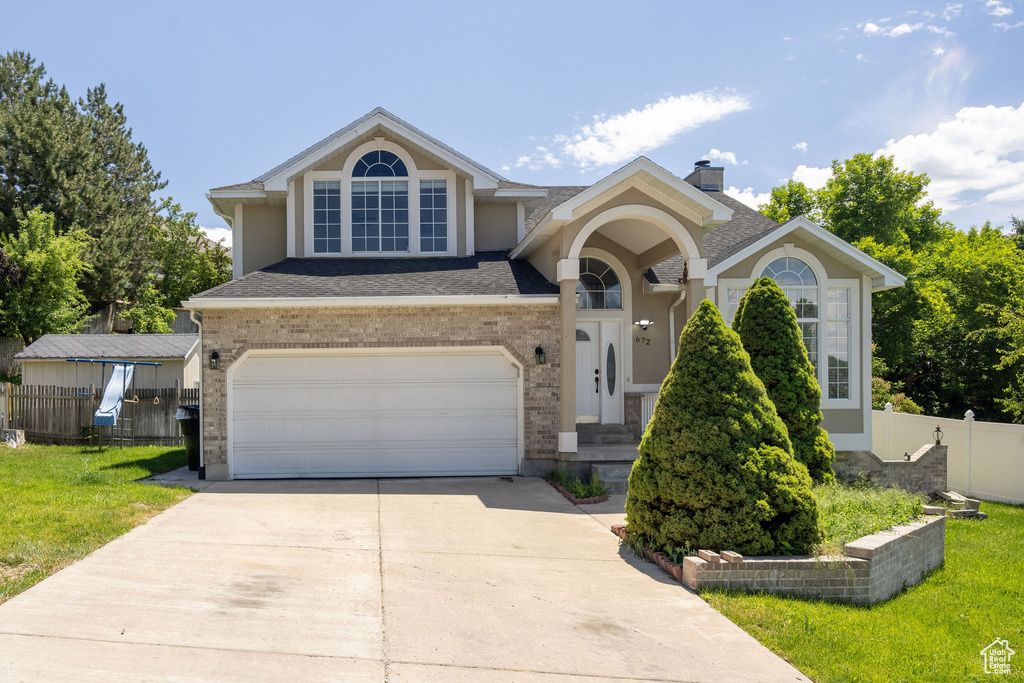 Traditional-style home with driveway, a garage, a chimney, stucco siding, and brick siding