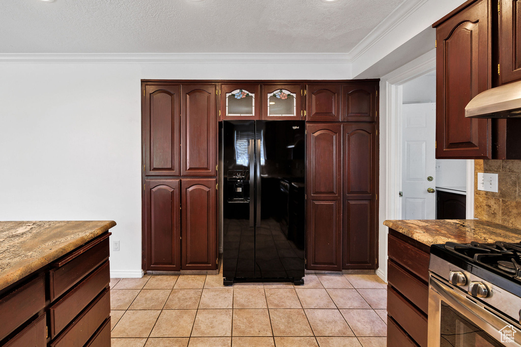 Kitchen featuring black fridge with ice dispenser, crown molding, gas stove, light tile patterned floors, and glass insert cabinets