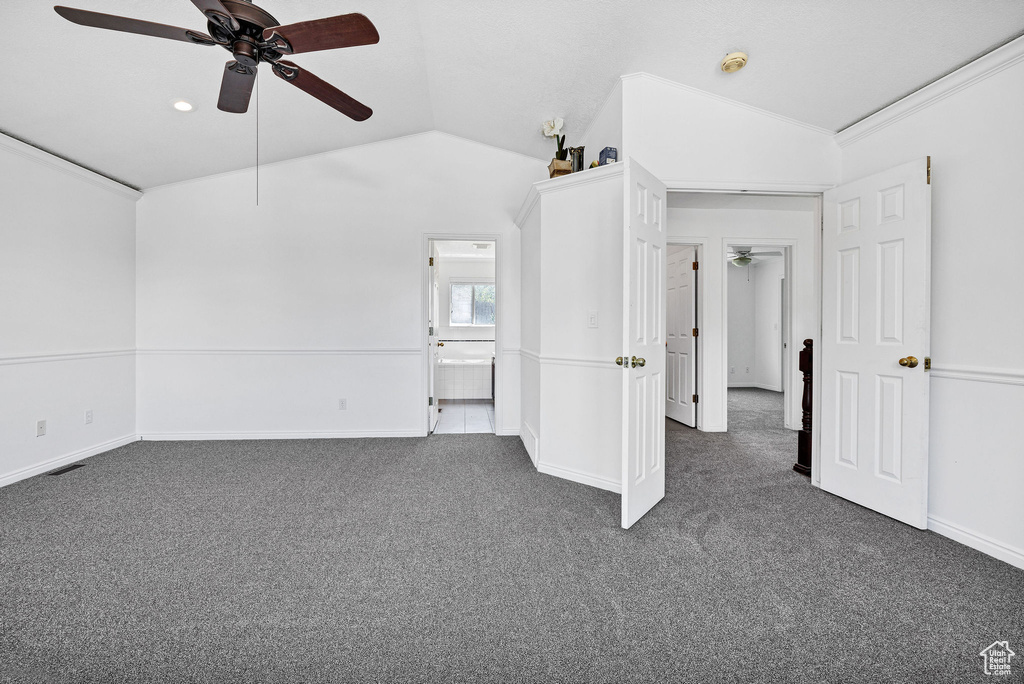 Unfurnished bedroom featuring vaulted ceiling, dark colored carpet, ceiling fan, ensuite bathroom, and ornamental molding