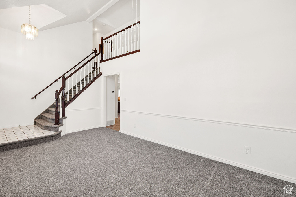 Stairway featuring carpet floors, a chandelier, and high vaulted ceiling