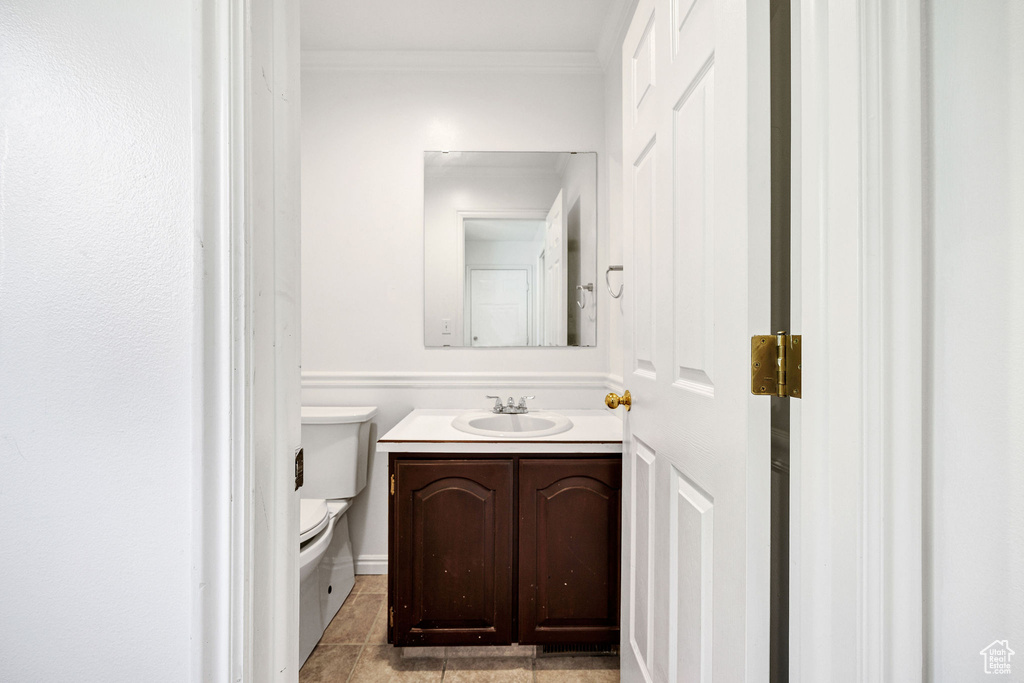 Half bathroom with vanity, crown molding, and tile patterned floors