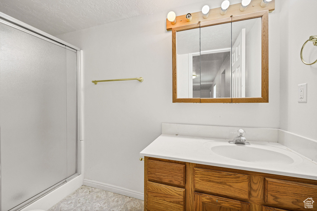 Full bathroom featuring a shower stall, vanity, and a textured ceiling