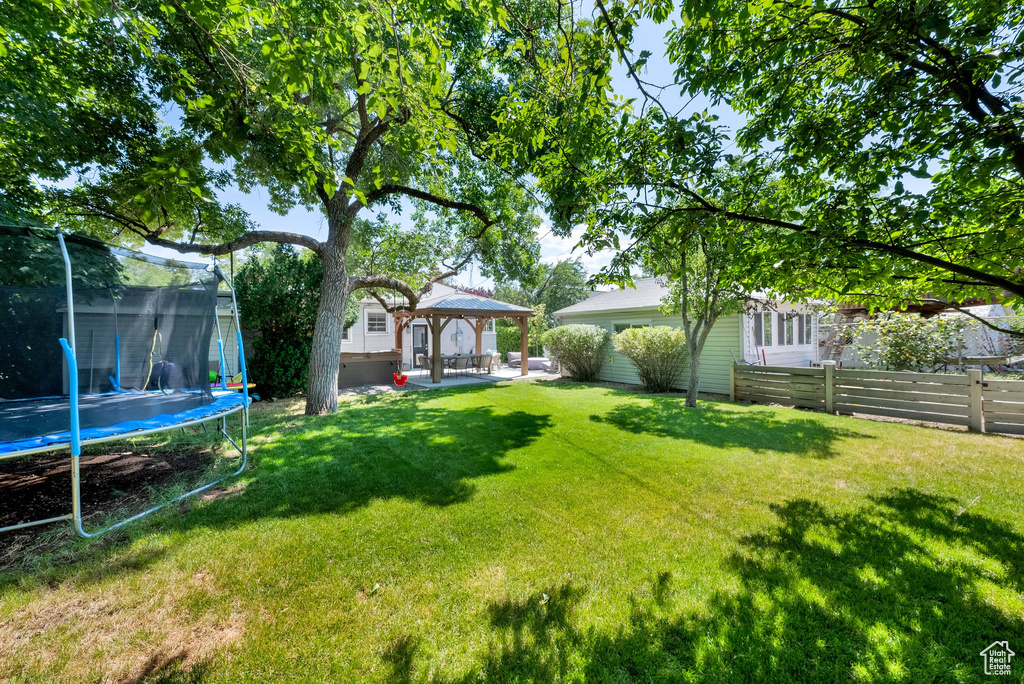 View of yard featuring a trampoline, a gazebo, and a patio area