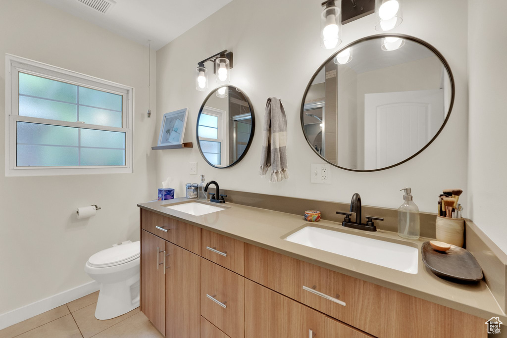 Bathroom with tile patterned floors, double vanity, toilet, and baseboards