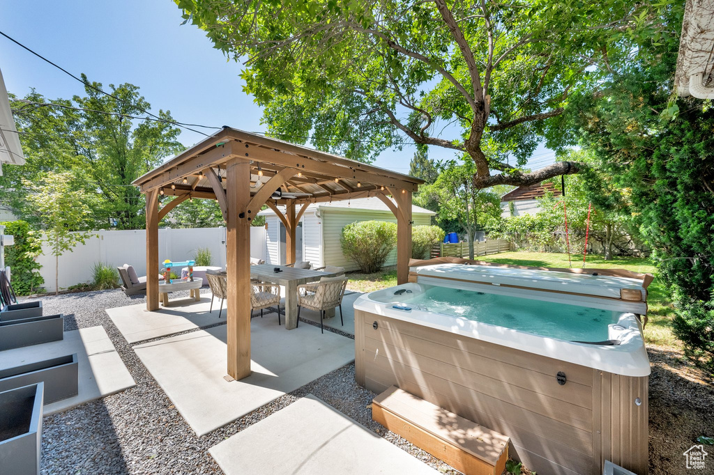 Fenced backyard featuring a hot tub, a patio, and a gazebo