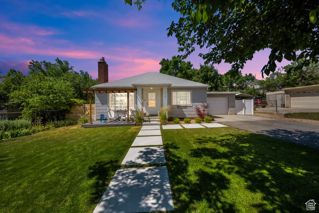 Ranch-style house featuring concrete driveway, a chimney, a garage, and covered porch