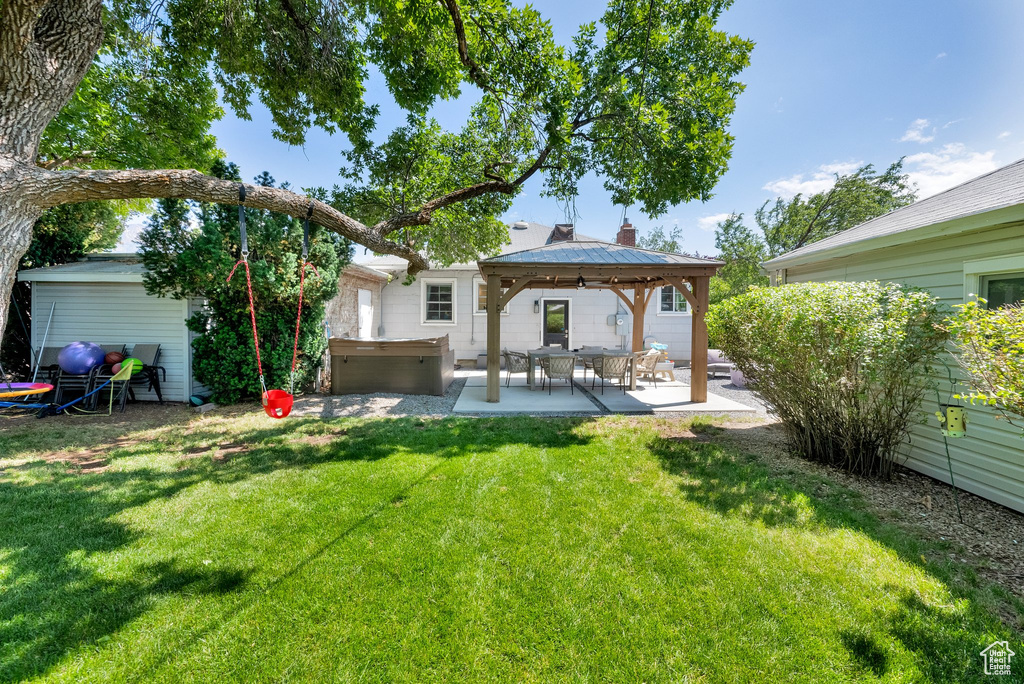 Back of house featuring a patio area, a hot tub, a gazebo, and a lawn