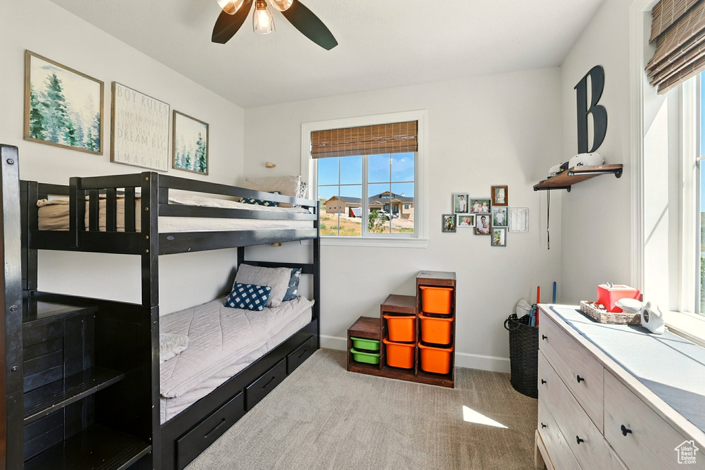 Carpeted bedroom with multiple windows and a ceiling fan
