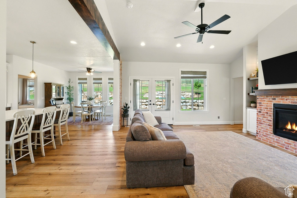 Living room featuring a ceiling fan, recessed lighting, a fireplace, light wood-style floors, and vaulted ceiling