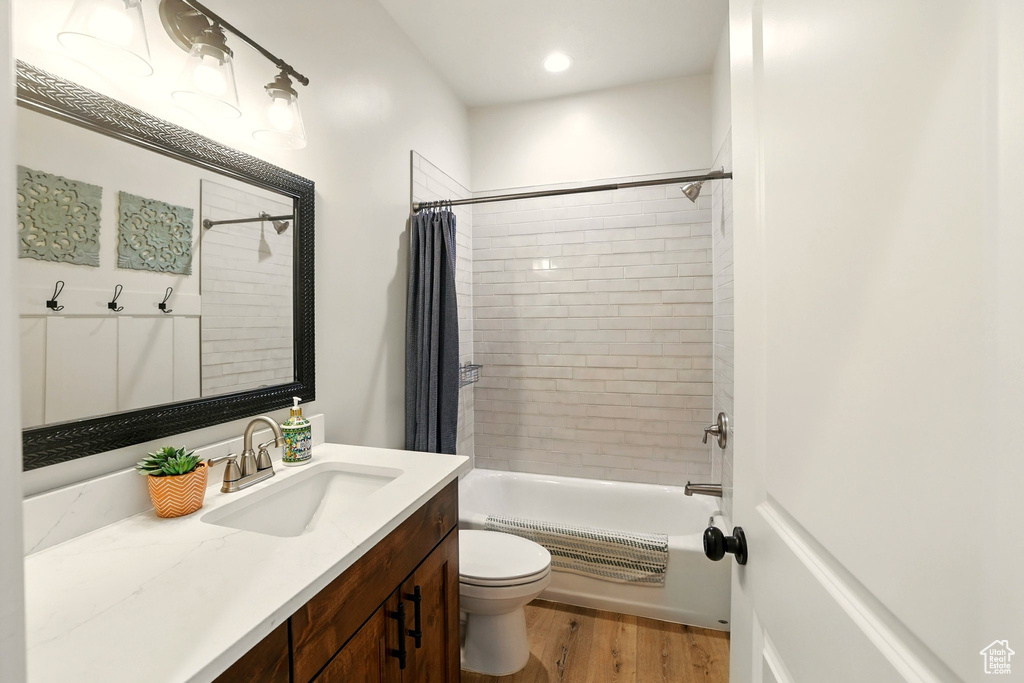 Full bathroom featuring vanity, shower / bathtub combination with curtain, and wood finished floors