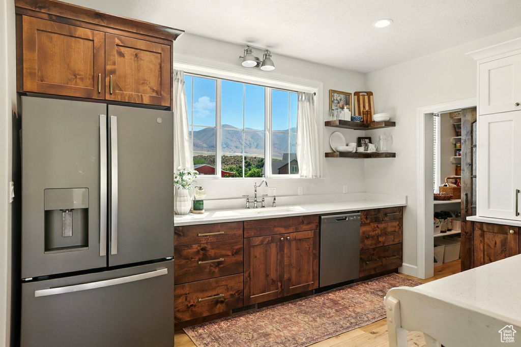 Kitchen with stainless steel appliances, light wood-style flooring, light countertops, a mountain view, and recessed lighting