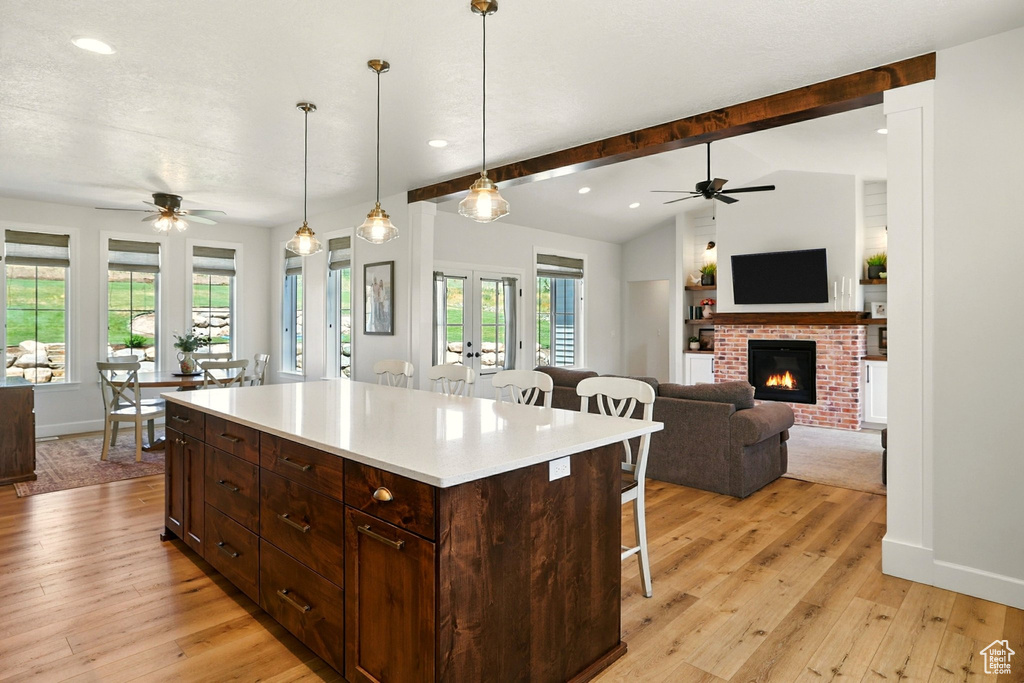 Kitchen with a ceiling fan, a breakfast bar area, recessed lighting, a brick fireplace, and light wood finished floors
