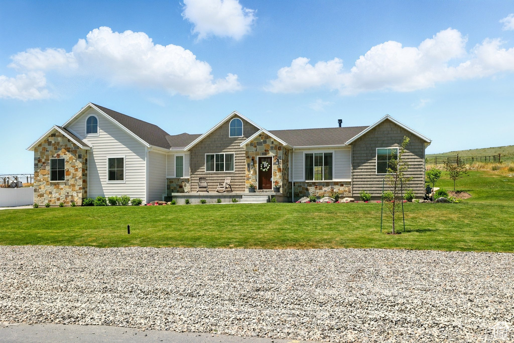 Single story home featuring stone siding and a front lawn