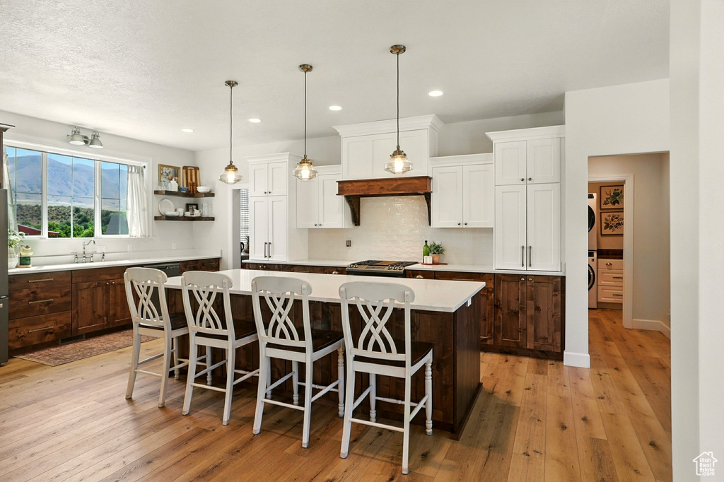 Kitchen featuring light countertops, a kitchen island, tasteful backsplash, white cabinetry, and light wood finished floors