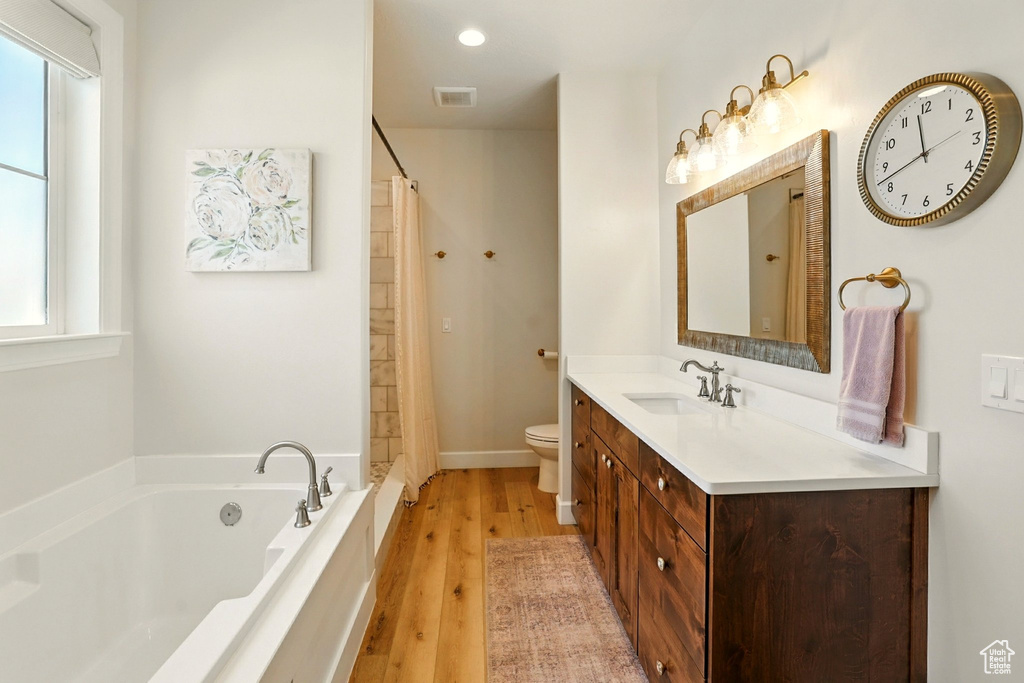 Bathroom with a garden tub, vanity, wood finished floors, a shower with curtain, and recessed lighting