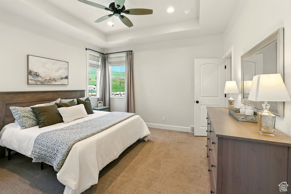 Bedroom featuring a raised ceiling, light colored carpet, ceiling fan, and recessed lighting