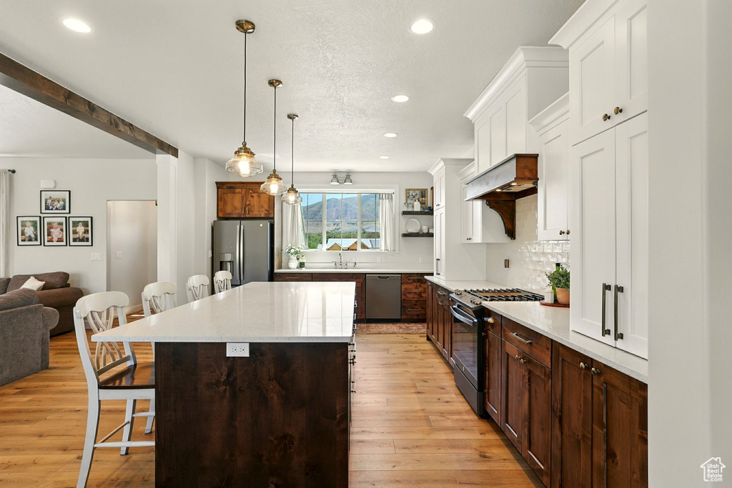 Kitchen featuring appliances with stainless steel finishes, a kitchen breakfast bar, recessed lighting, light countertops, and light wood-style flooring