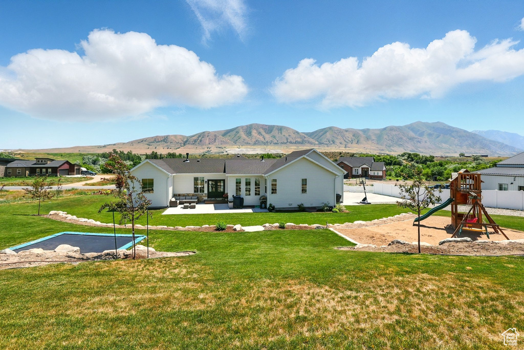 Back of house featuring a playground, a mountain view, a patio, and outdoor lounge area
