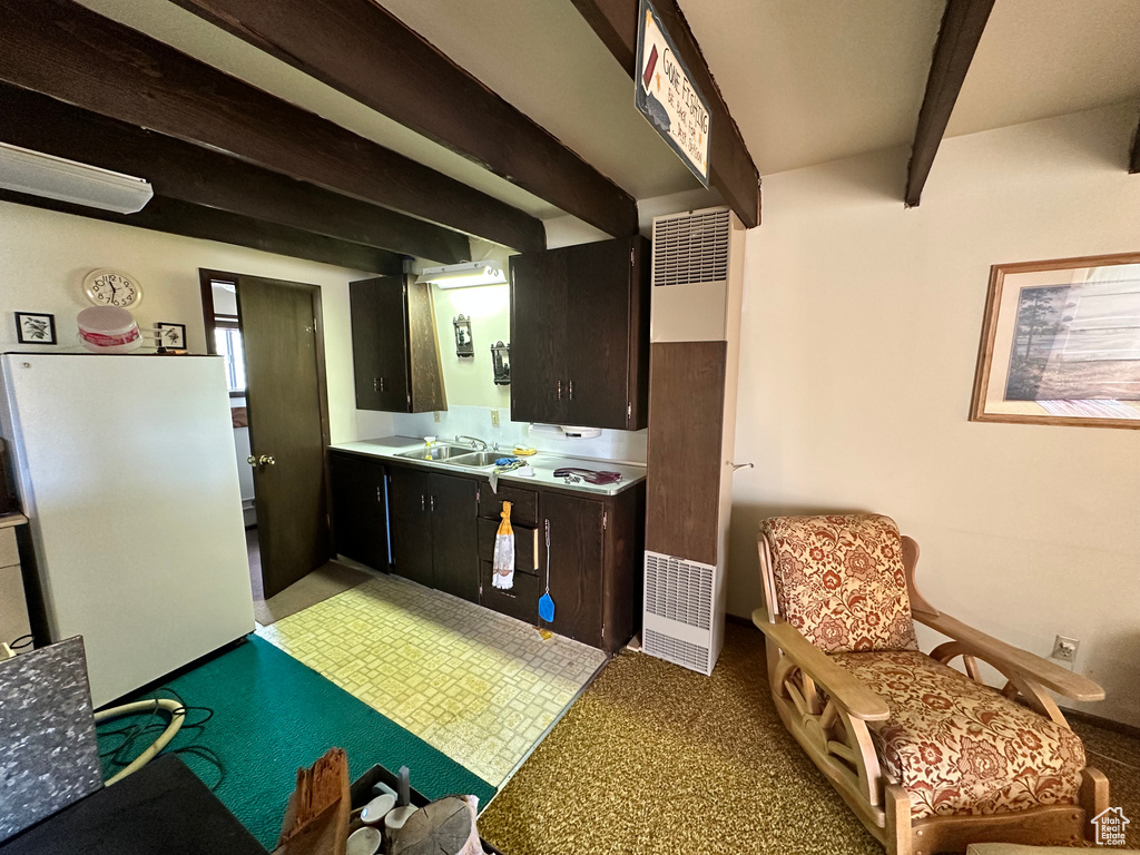 Kitchen with beamed ceiling, a heating unit, light countertops, and freestanding refrigerator