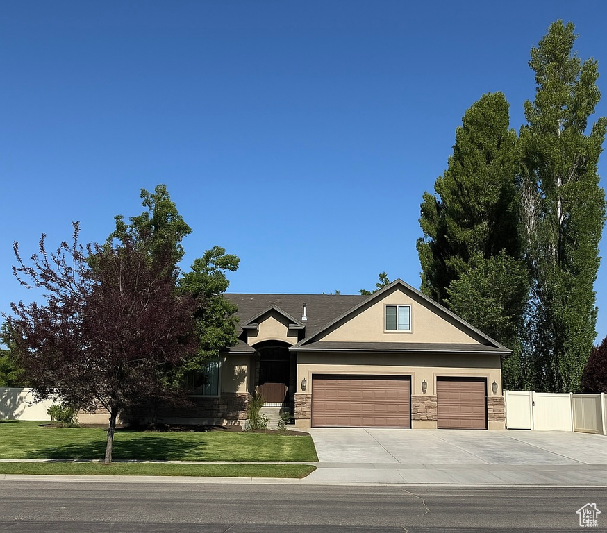 Single story home with stucco siding, concrete driveway, stone siding, and a garage