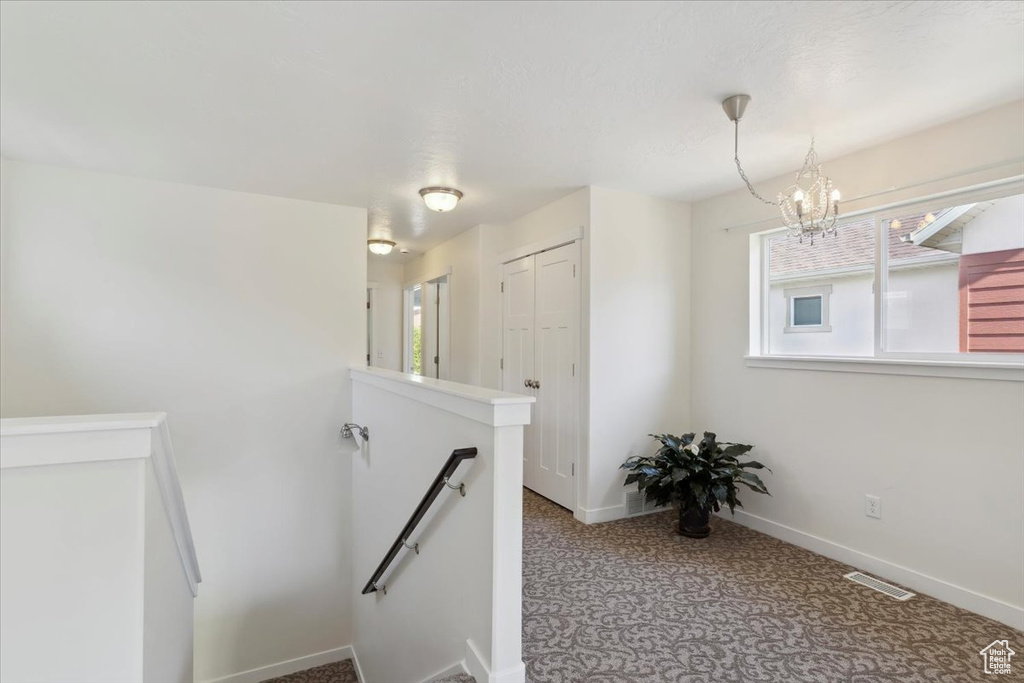 Staircase with a chandelier and carpet flooring