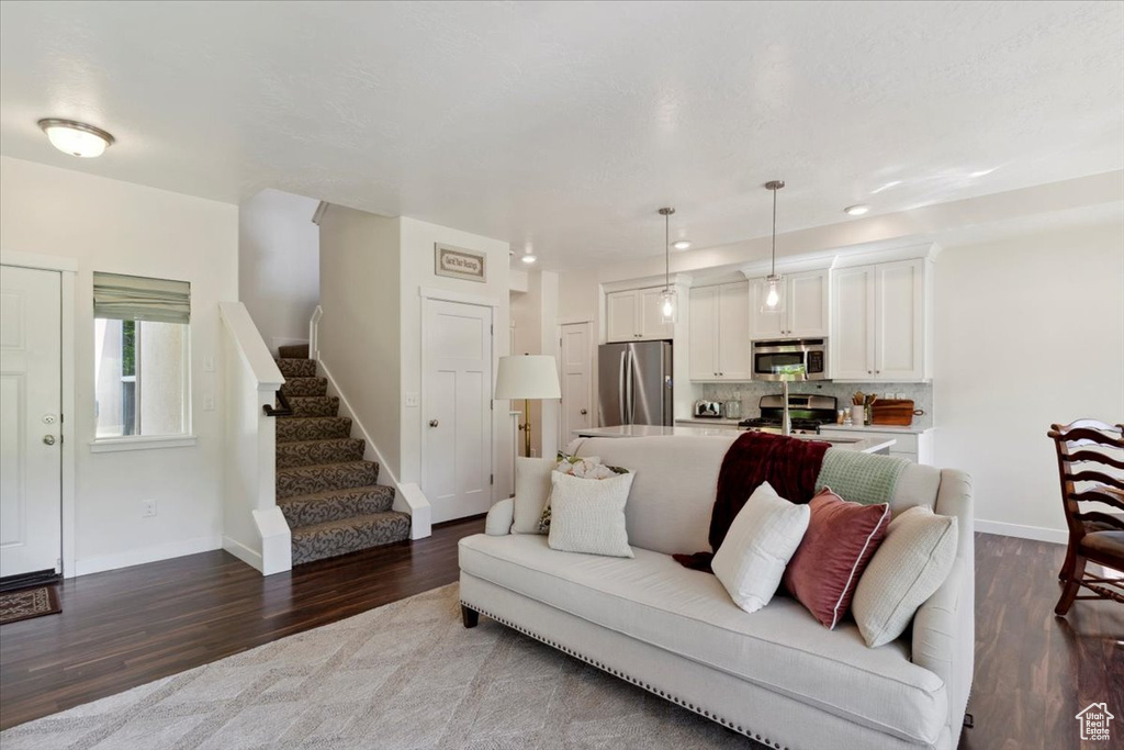 Living room with dark wood-style flooring, stairway, and recessed lighting