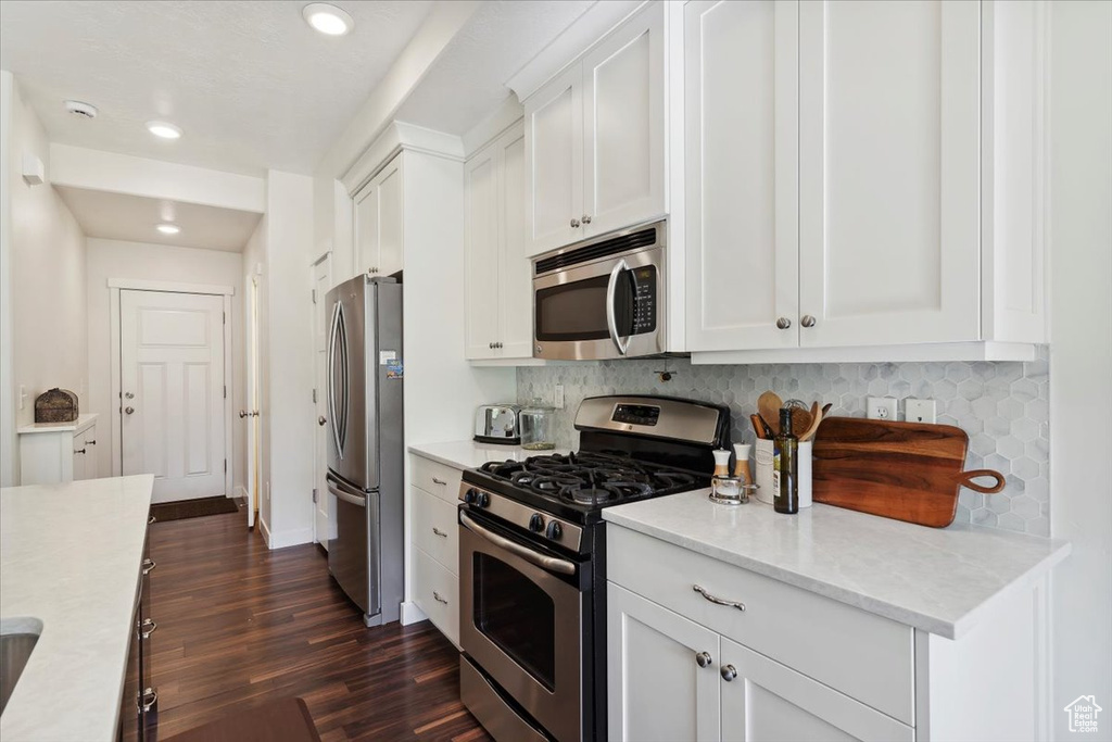 Kitchen featuring appliances with stainless steel finishes, decorative backsplash, dark wood-style floors, white cabinets, and recessed lighting