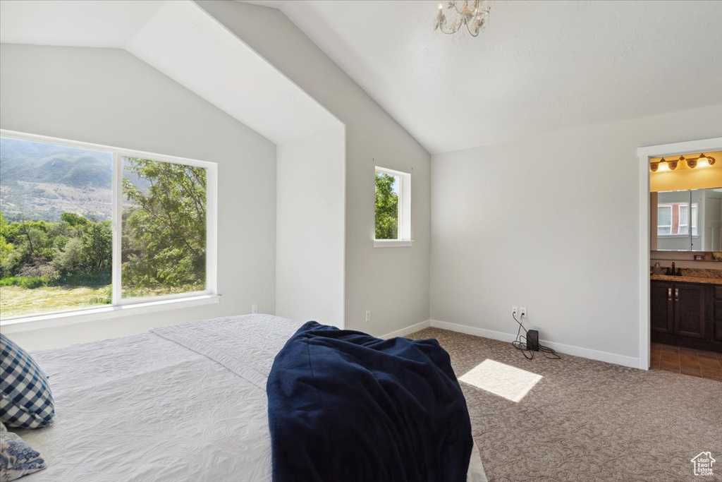 Bedroom with carpet floors, vaulted ceiling, ensuite bathroom, and a chandelier