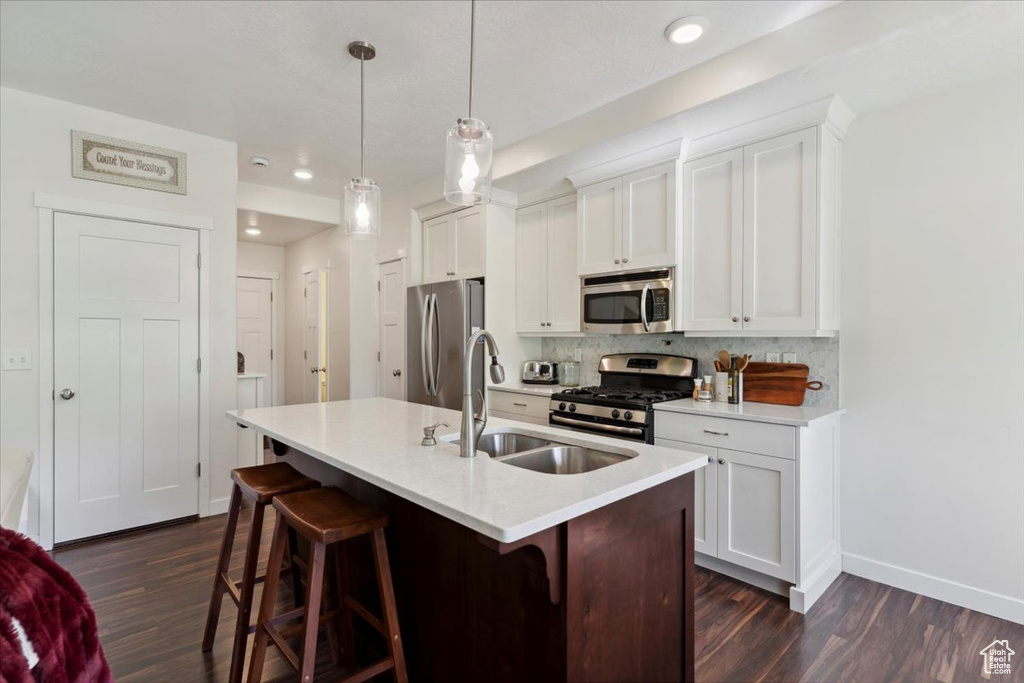 Kitchen with stainless steel appliances, dark wood-style flooring, a kitchen island with sink, a kitchen bar, and recessed lighting
