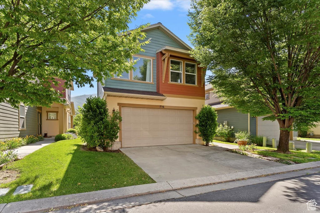 View of front of house featuring a garage, concrete driveway, stucco siding, and a front yard