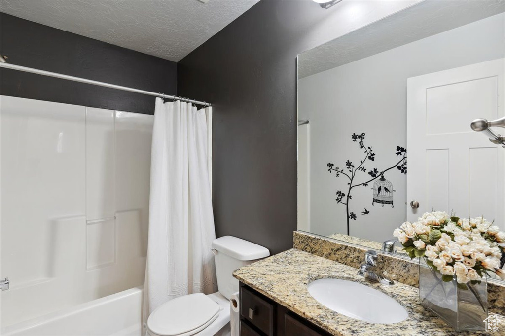 Bathroom featuring vanity, a textured ceiling, and shower / bathtub combination with curtain