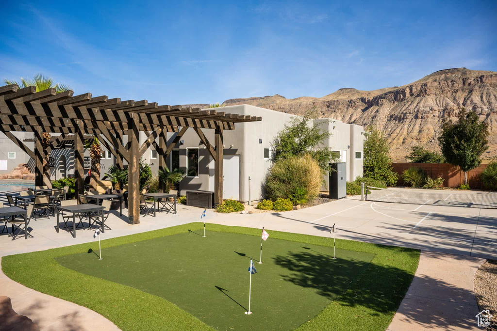 View of community featuring a putting area, a pergola, a mountain view, and a patio area
