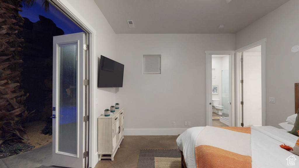 Bedroom featuring a spacious closet, tile patterned floors, and ensuite bathroom