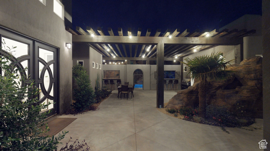 Patio at night featuring a patio area, a pergola, and outdoor dining space