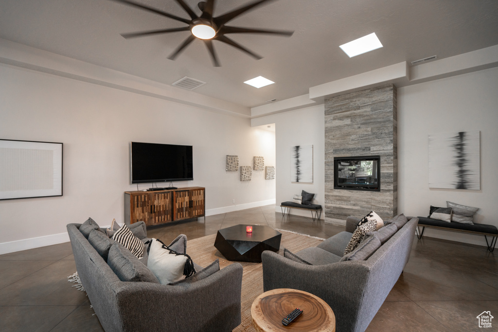 Living area with ceiling fan, a large fireplace, and concrete flooring