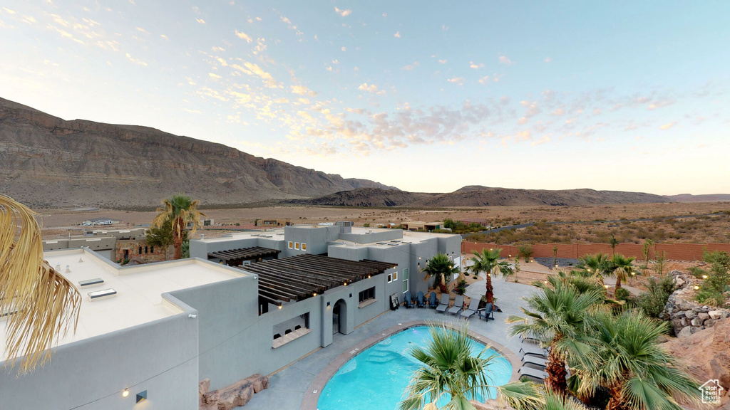 Pool at dusk featuring a mountain view, a fenced backyard, and a patio area
