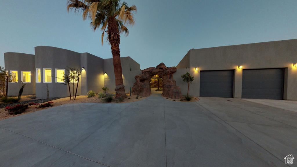 Pueblo revival-style home with driveway, an attached garage, and stucco siding