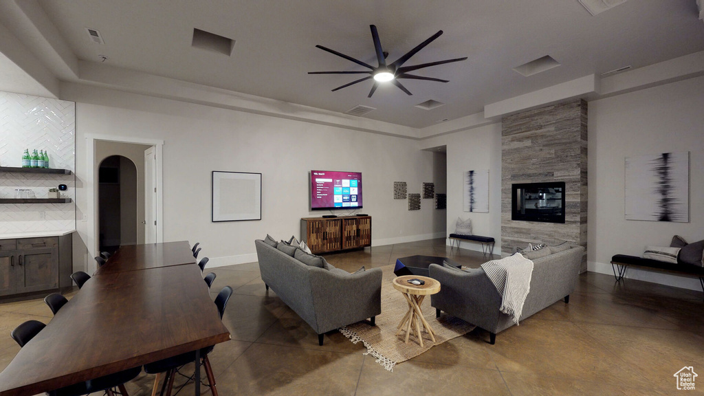 Living area featuring ceiling fan, a large fireplace, and arched walkways