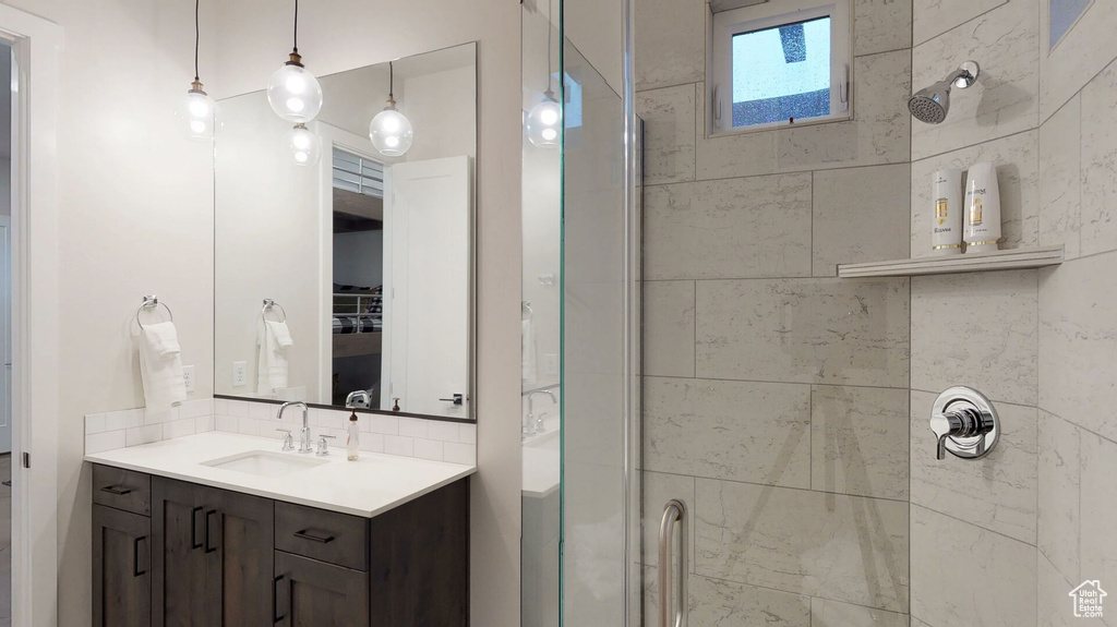 Bathroom with a stall shower, vanity, and decorative backsplash