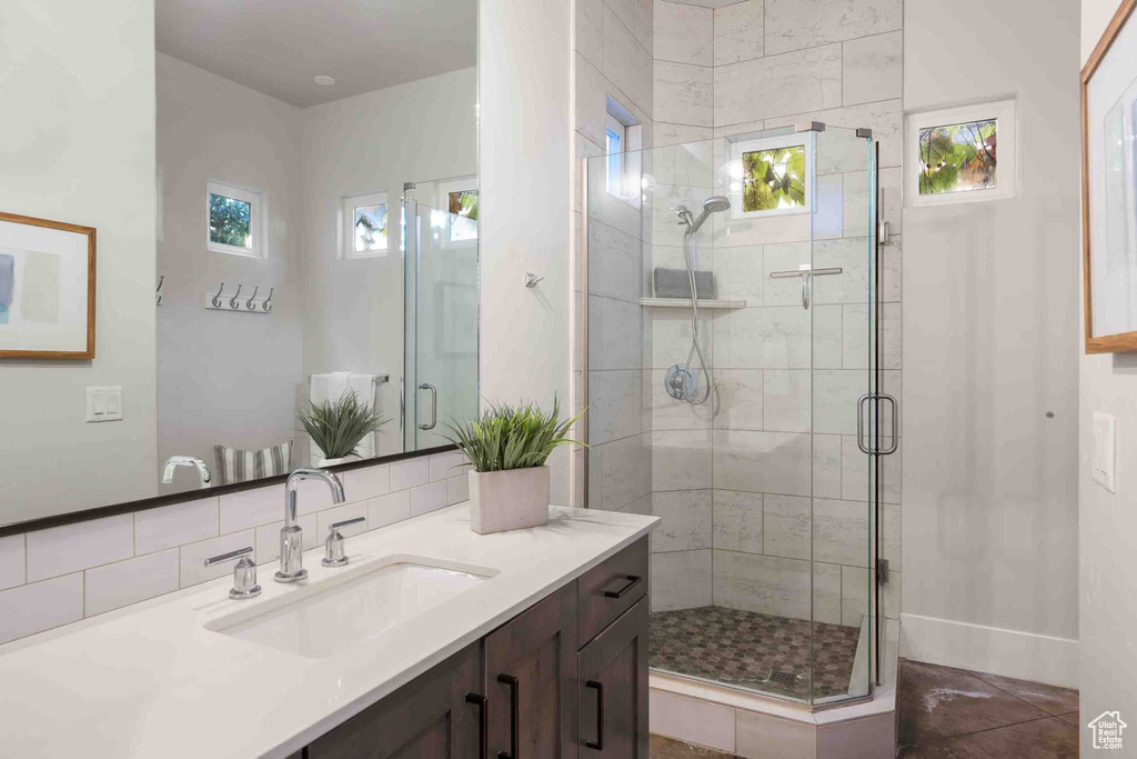 Bathroom featuring vanity, a shower stall, and decorative backsplash