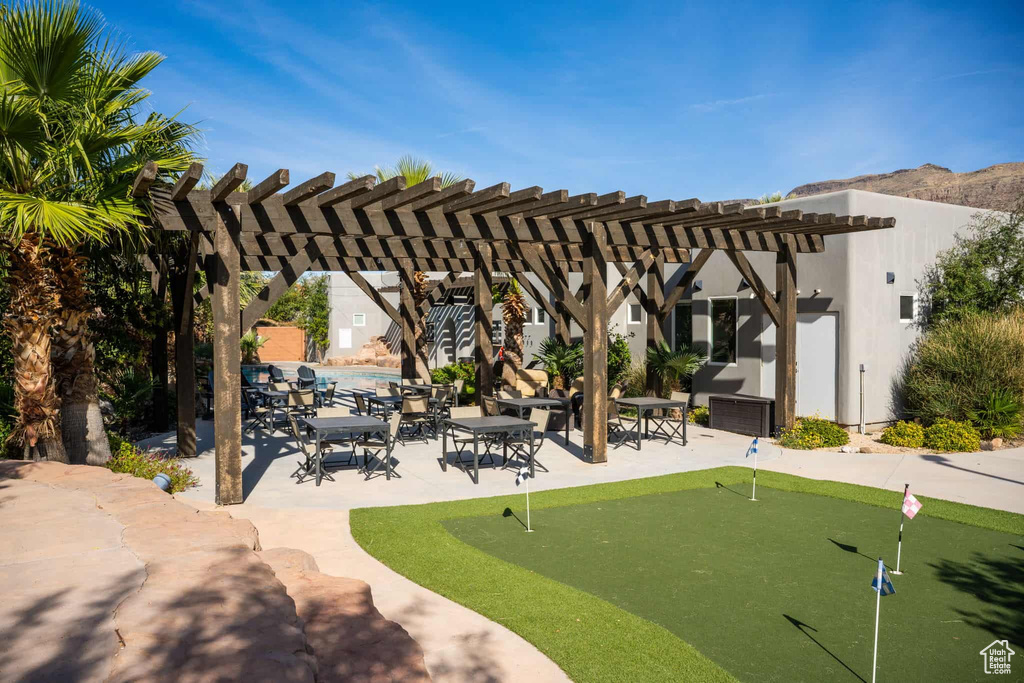 View of community featuring an area to practice putting, a pergola, and a patio