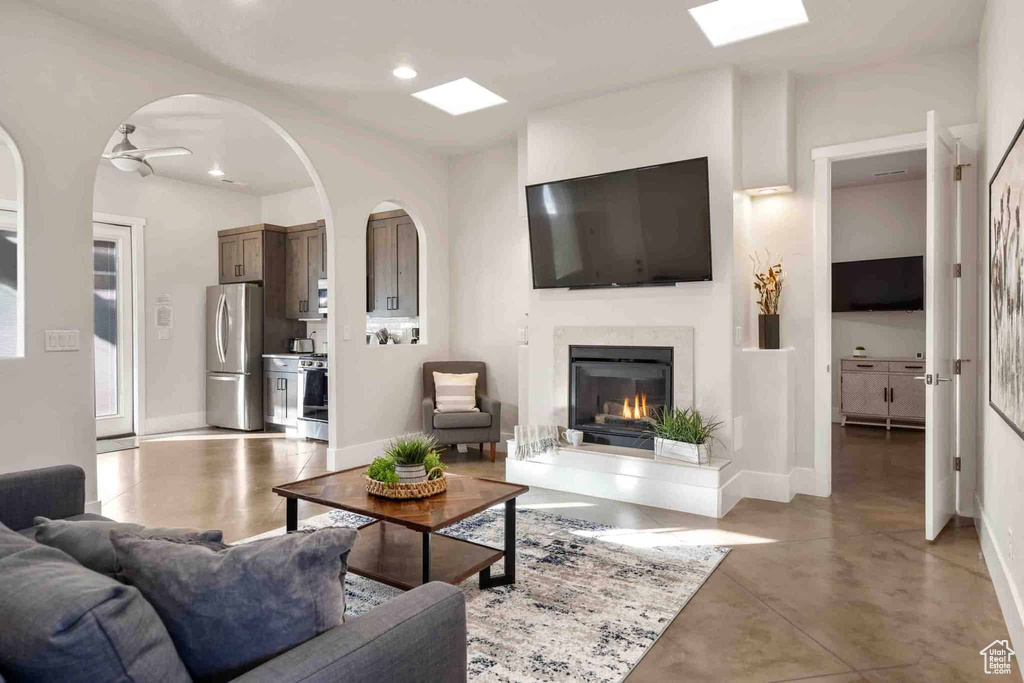 Living area with a high end fireplace, ceiling fan, recessed lighting, and concrete floors
