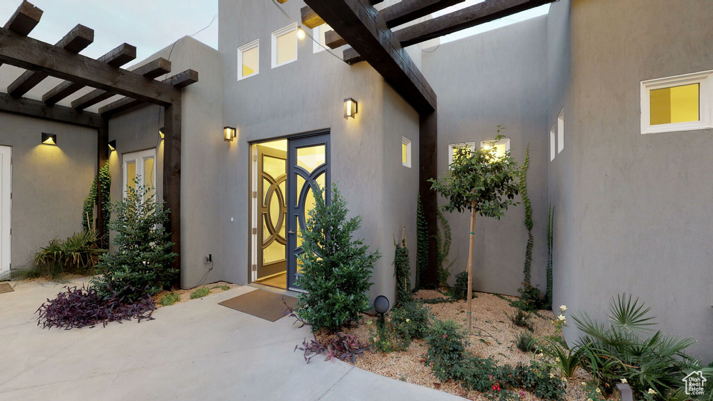 View of exterior entry with french doors, stucco siding, and a patio