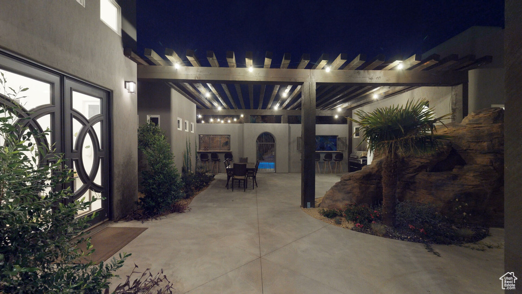 Patio at night with a patio, outdoor dining space, and a pergola