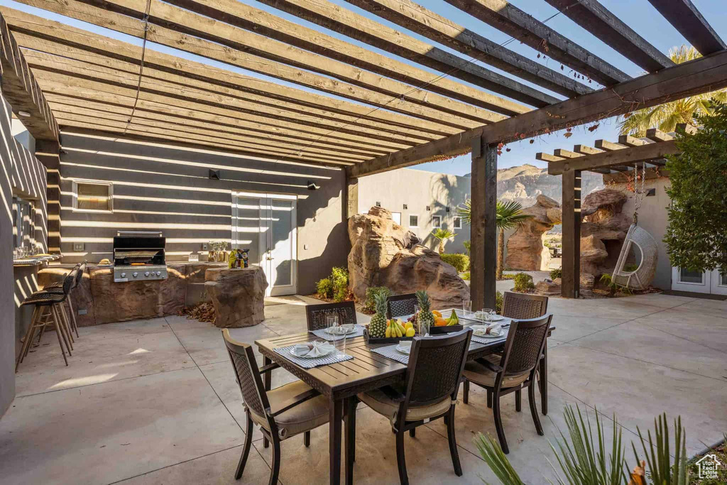 View of patio with area for grilling, a pergola, outdoor dining space, and a mountain view