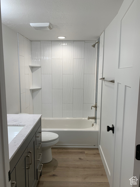 Bathroom with vanity, wood finished floors, tub / shower combination, and a textured ceiling