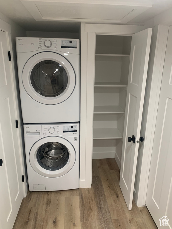 Laundry area with stacked washing machine and dryer and light wood-style floors