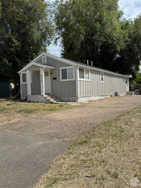 View of front facade featuring board and batten siding and asphalt driveway